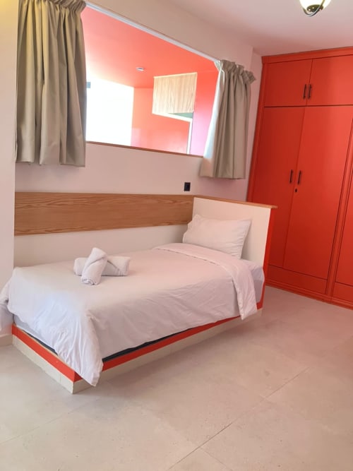 Modern bedroom at SAMYAflat in Tangier with red accent walls, queen bed, flat-screen TV, and wardrobe storage