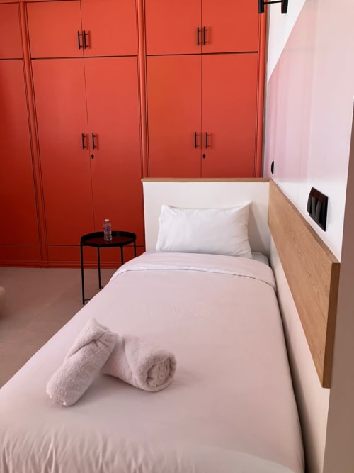 Modern bedroom at SAMYAflat Tangier with red wardrobes, wood bed frame, white bedding, and rolled towels