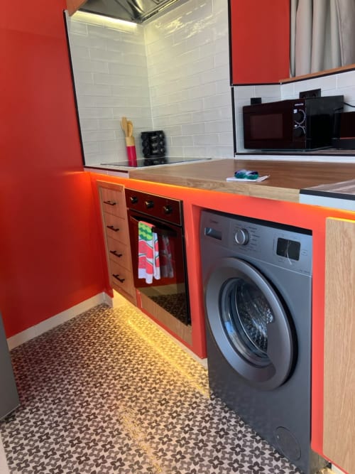Modern red kitchen with washing machine, oven, and white subway tile backsplash at SAMYAflat apartment in Tangier