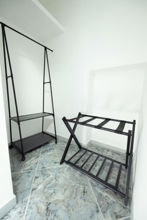 Camera da letto minimalista dell'appartamento Newhouse a Modugno con letto in ferro battuto nero e portabagagli su pavimento in marmo