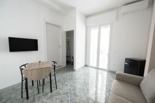 Moderno soggiorno con sala da pranzo, TV a schermo piatto, pavimento in marmo e porte vetrate verso il giardino