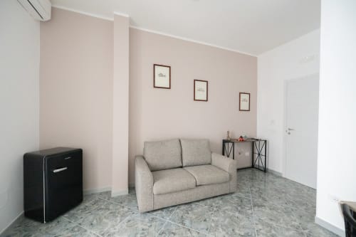 Moderno soggiorno con divano beige, pavimento in piastrelle grigie e pareti rosa nell'appartamento Newhouse a Modugno, Italia