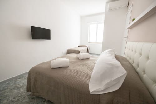 Camera moderna nell'appartamento Francy and sons, hotel Newhouse a Modugno con testata imbottita bianca, TV e