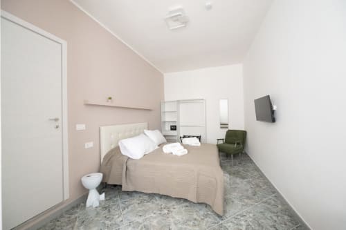 Camera da letto moderna all'appartamento Newhouse di Modugno con letto matrimoniale, TV e poltrona verde
