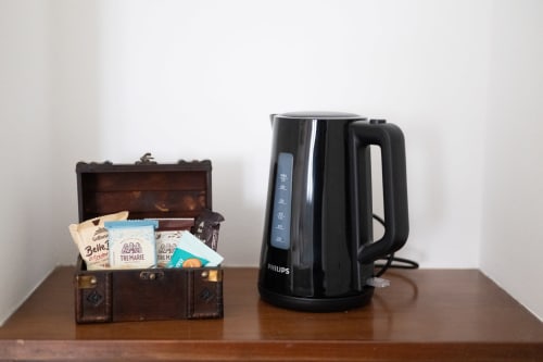 Valigia d'epoca con bustine di tè e bollitore elettrico Philips su tavolo in legno all'appartamento Newhouse di Modugno