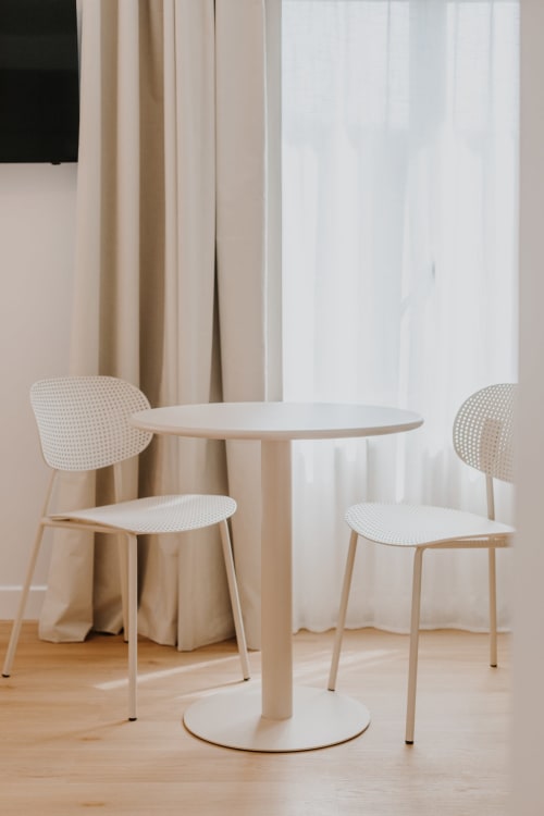 Ambiance minimaliste à la Villa des Fleurs avec table ronde blanche et chaises légères dans la chambre Rose