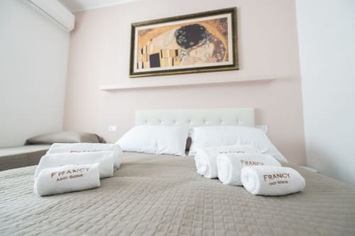 Camera Francy 3 dell'hotel Newhouse a Bari con asciugamani bianchi sul letto e opere d'arte