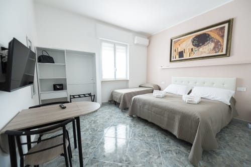 Camera d'hotel Newhouse a Bari con due letti, TV, scrivania, armadio e comfort moderni