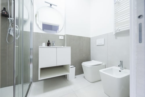 Bagno moderno nella camera Francy 3 dell'hotel Newhouse a Bari, con sanitari bianchi, piastrelle grigie e box doccia