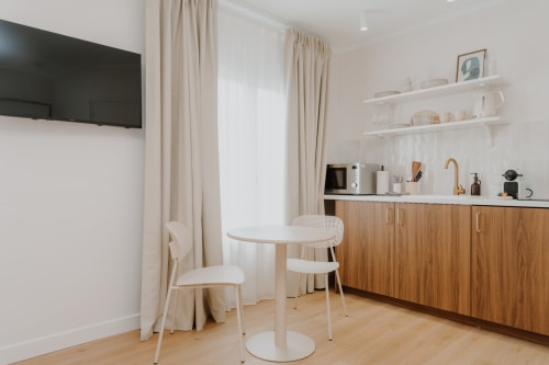Kitchenette moderne avec meubles en bois, table à manger et TV dans la chambre Mimosa de la Villa des Fleurs, Blonville sur Mer