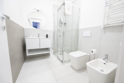 Bagno moderno dell'hotel Newhouse di Bari con sanitari bianchi, cabina doccia in vetro e scaldasalviette