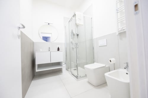 Bagno moderno e luminoso dell'hotel Newhouse Bari con lavabo, toilette, bidet e doccia con box in vetro
