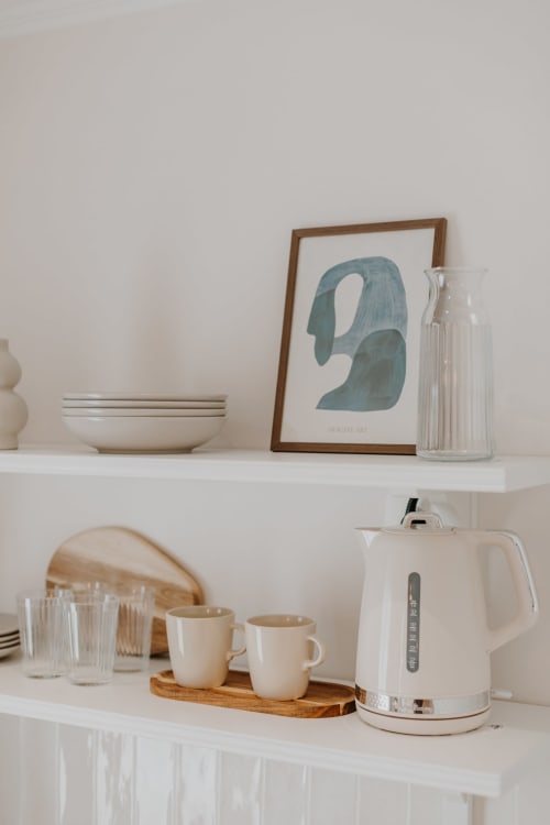 Étagère minimaliste à la Villa des Fleurs avec bouilloire blanche, tasses, verres et art abstrait encadré à Blonville sur Mer