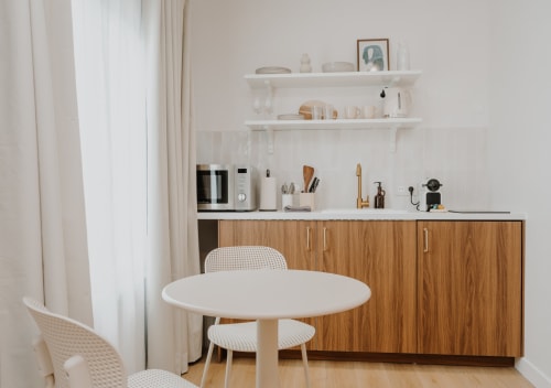 Kitchenette moderne à la Villa des Fleurs : table ronde blanche, meubles bois et étagères ouvertes à Blonville sur Mer