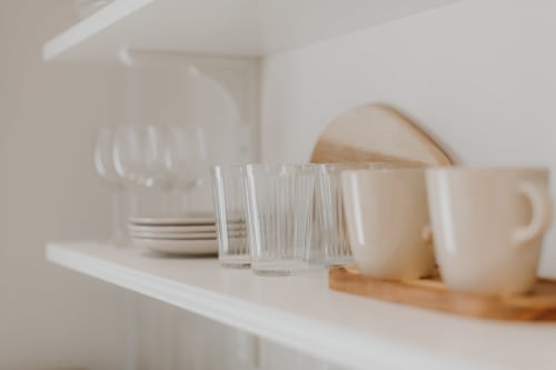 Étagère minimaliste blanche présentant verres, tasses en céramique et assiettes empilées à la Villa des Fleurs, Blonville sur Mer
