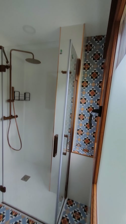 Modern shower enclosure with brass fixtures and geometric tile accents at Vacationgalicia in Pantón, Lugo