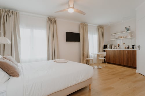 Chambre moderne à la Villa des Fleurs B&B à Blonville sur Mer avec lit blanc, mobilier bois, kitchenette et vue sur la ville