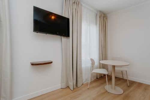 Chambre moderne de la Villa des Fleurs avec téléviseur mural, table ronde et vue sur la ville à Blonville-sur-Mer