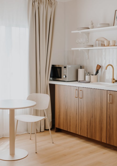 Kitchenette moderne à la Villa des Fleurs Blonville sur Mer avec meubles en bois, étagères blanches et table de salle à manger