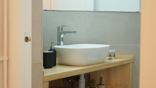 Moderno mueble de baño con lavabo blanco y grifo cromado en el apartamento BCNMADflats Barcelona