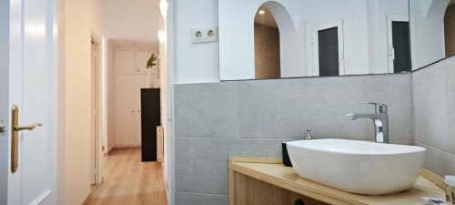 Cuarto de baño moderno en Barcelona Art de BCNMADflats con lavamanos blanco, paredes de azulejos grises y mueble de madera
