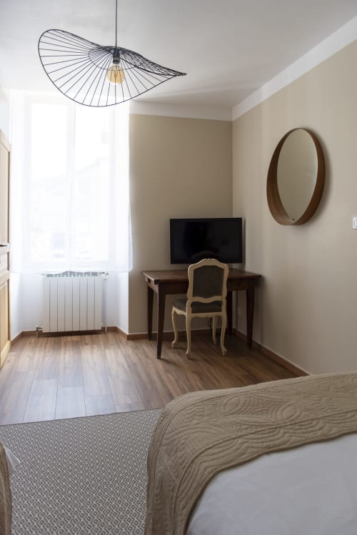 Chambre moderne à La Demeure du Comte avec télévision écran plat, bureau, mobilier en bois et lampe suspendue à Marcillac-Vallon