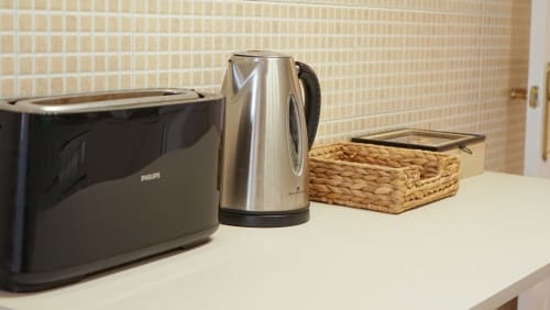 Encimera de cocina con tostador Philips, tetera de acero inoxidable y salvamanteles tejidos en el apartamento BCNMADflats Barcelona