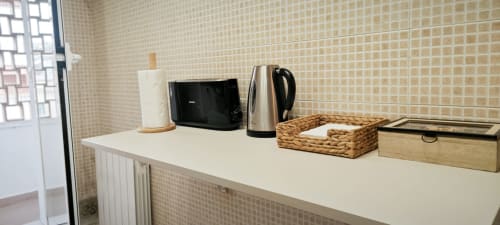 Encimera de cocina en apartamento artístico de Barcelona con hervidor, microondas, servilletas y cestas de almacenamiento