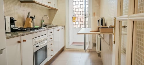 Cocina moderna en apartamento Art de Barcelona con muebles blancos, encimera de granito, estufa de gas y azulejos de salpicaduras