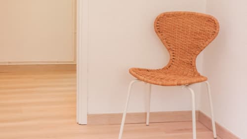 Silla de ratán tejido moderno con patas metálicas blancas en salón de apartamento barcelonés