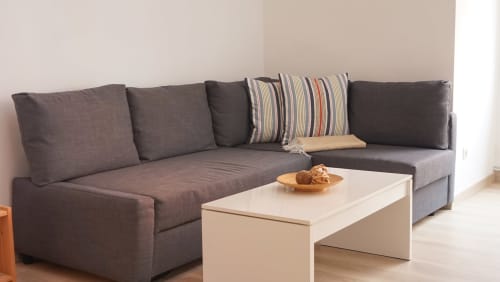 Sofá seccional gris moderno con cojín rayado en salón de apartamento en Barcelona