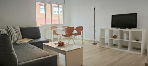 Sala de estar de apartamento moderno en Barcelona con sofá, comedor, televisor y estanterías empotradas - Art apartment BCNMADflats