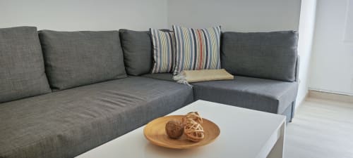 Sofá gris moderno de esquina con cojines a rayas en Barcelona - Apartamento Art del hotel BCNMADflats, mesa de café blanca con