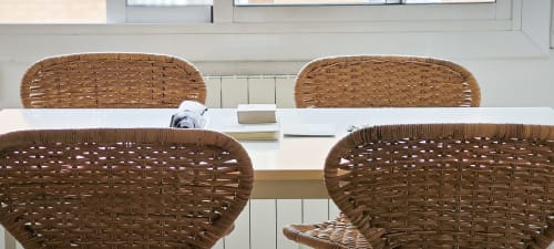 Sillas de ratán tejido en mesa de comedor blanca en apartamento Art de Barcelona en hotel BCNMADflats