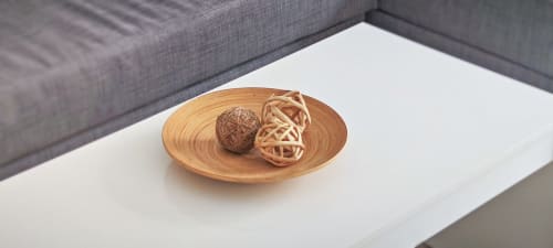 Cuenco de madera con bolas tejidas decorativas sobre mesa blanca junto a sofá gris en apartamento de Barcelona