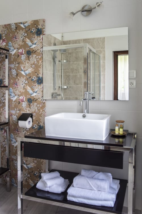 Lavabo moderne avec vasque blanche, meuble noir, miroir et serviettes fraîches à La Demeure du Comte