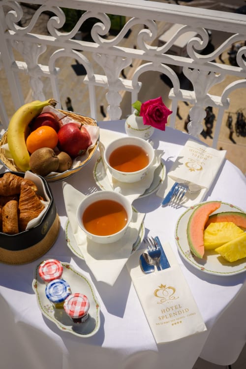 Élégant petit-déjeuner à l'Hôtel Splendide Cannes avec viennoiseries, fruits frais, thé et fleurs