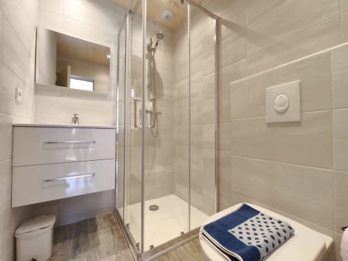Salle de bain moderne de l'appartement Chalet Coste Belle avec douche en verre, meuble vasque blanc et sèche-serviettes électrique