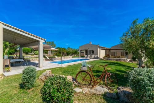 Villa moderna en Artà con piscina, jardín cuidado, terraza cubierta y bicicleta rústica en el césped