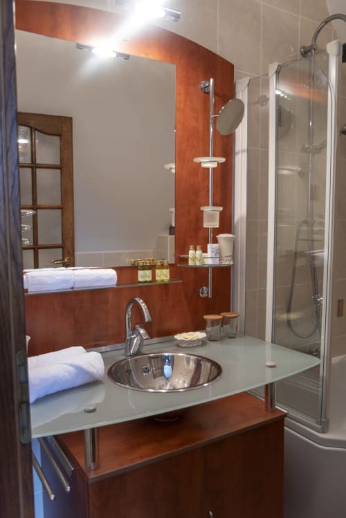 Salle de bains moderne avec vasque ronde, meuble en bois, grand miroir et douche à l'italienne à La Demeure du Comte, Marcillac-Vallon