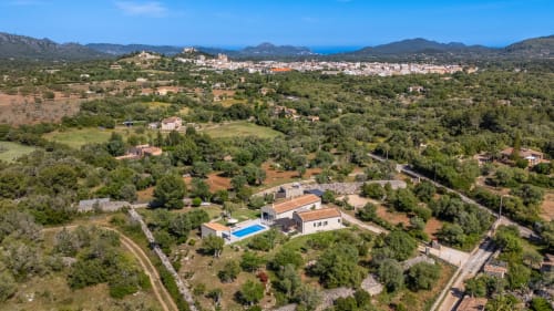 Villa moderna con piscina y jardín en la campiña de Artà, rodeada de árboles y montañas
