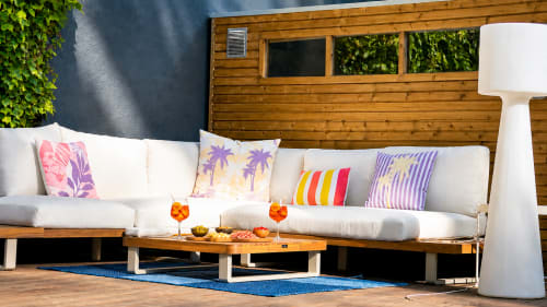 Espace lounge extérieur à Villa Avril & Spa à Sélestat avec mobilier en bois, coussins blancs et colorés.