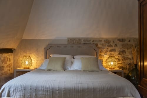 Chambre élégante à La Bohème, La Demeure du Comte avec lit capitonné, draps blancs, lampes tressées et papier peint fleuri