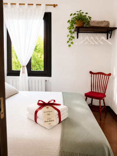 Cozy hotel room at Mas Ribas Hotel with white towels, red chair, and garden views in Palamós