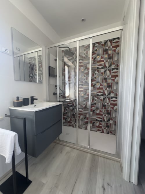 Bagno moderno al Casale Rusignûl B&B con vanity nero, doccia in piastrelle geometriche e pareti bianche