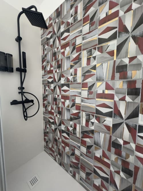 Doccia moderna con soffione a pioggia nero nel bagno di Casale Rusignûl, con piastrelle geometriche in bordeaux