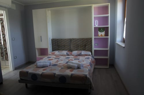 Camera moderna al Casale Rusignûl B&B di Cassegliano con biancheria a motivi, scaffali viola e arredi contemporanei