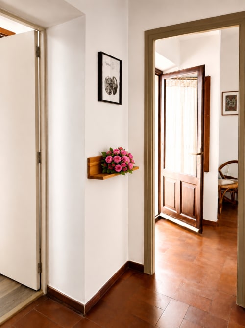 Passadís modern de l'Hotel Mas Ribas a Palamós amb portes de fusta, roses roses en prestatge i sòl de teracota