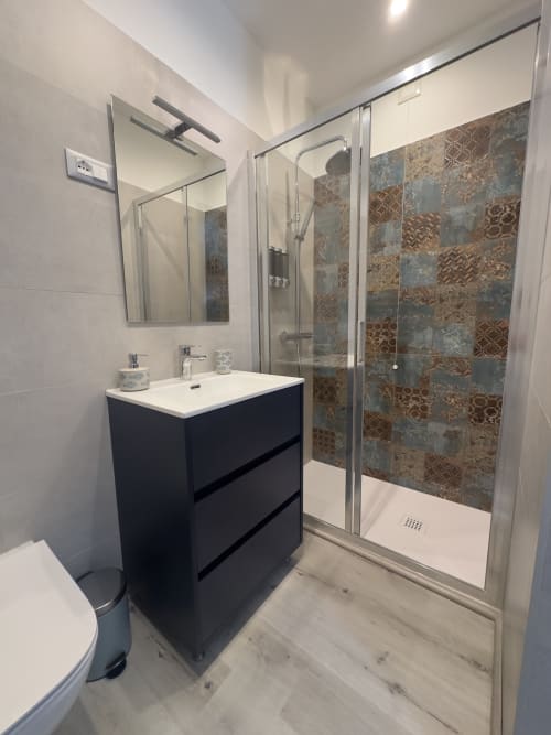 Bagno moderno at Casale Rusignûl B&B con vanità nera, specchio, piastrelle decorate e box doccia in vetro