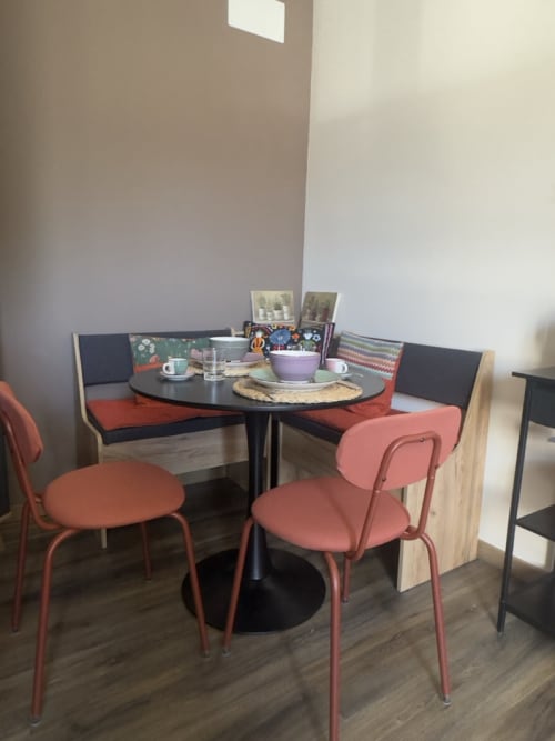 Zona pranzo moderna al Casale Rusignûl B&B con tavolo tondo nero, sedie corallo e panca blu a Basegliano, Italia